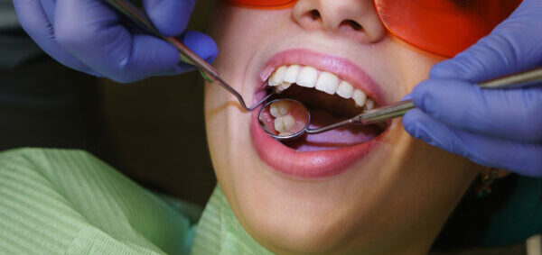Dentist makes routine inspection of teeth and gums. Girl patient in dental clinic. Close-up.