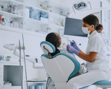 Dentist examining a patient in a modern dental clinic. Professional dental care and hygiene practice.